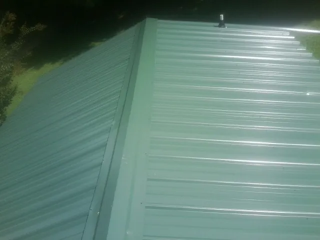 New green metal panels meeting at the ridge of a roof — Flat Roof Repair work by our crew in Ashville