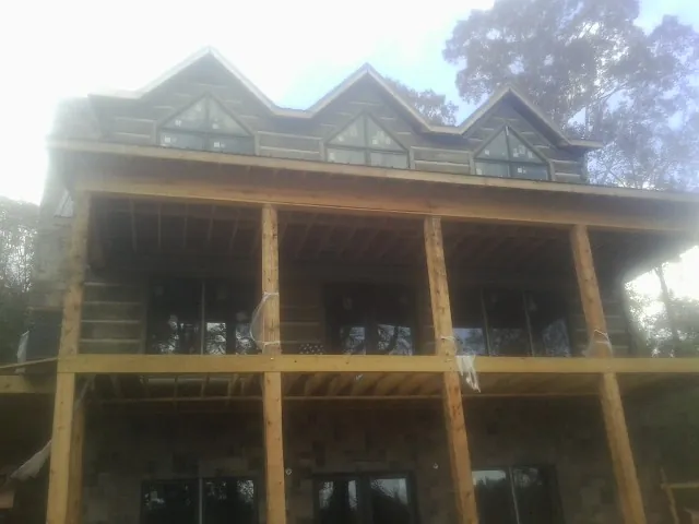 Dormers and porch framing on a large log home under construction — Roof Coating work by our crew in Ashville