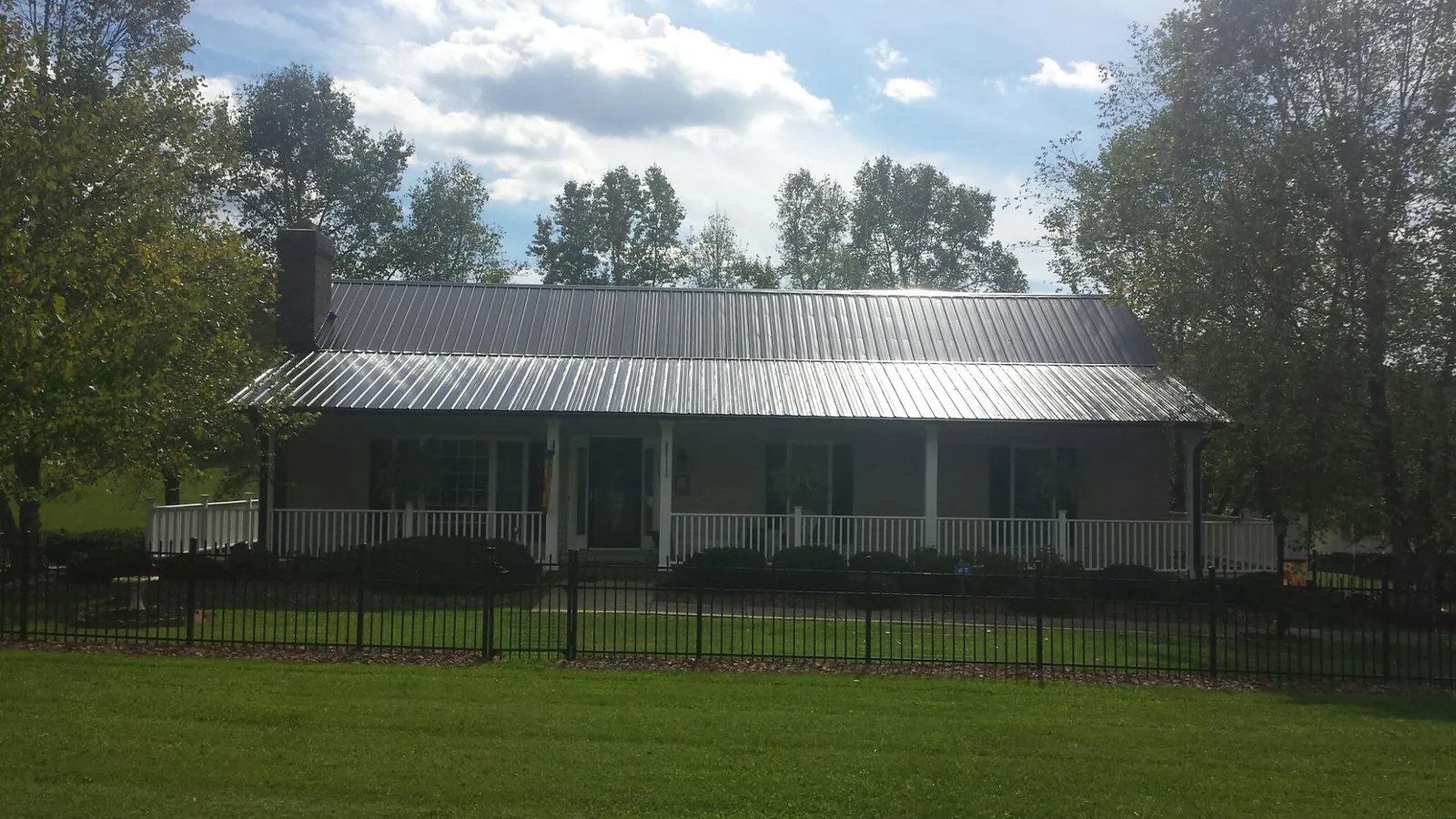 Gray metal roof on a brick ranch with a full width front porch — Gutter Guard Installation work by our crew in Ashville